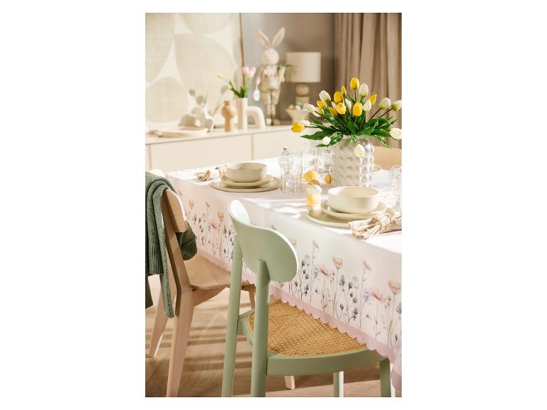 Table de Pâques dressée avec une nappe à motifs floraux, des tulipes jaunes et blanches, et des décorations de lapin.