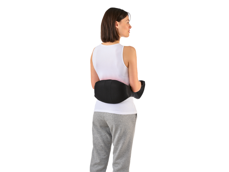 Femme avec masseur lombaire électrique et pantalon de survêtement gris.