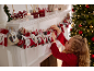 Fille ouvrant un calendrier de l'avent en tissu sur une cheminée de Noël.