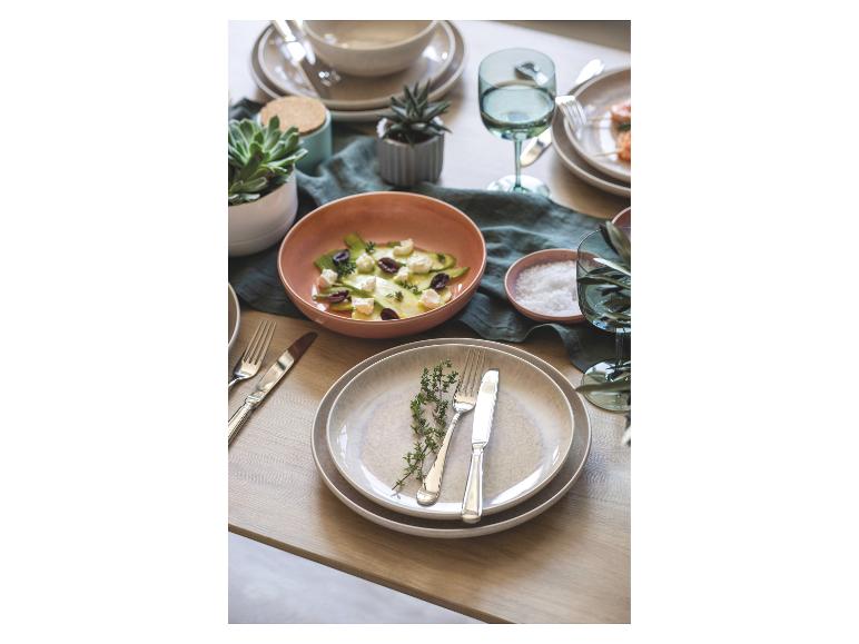 Table dressée avec des plats, dont une salade, et des couverts.