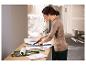 Femme coupant du papier peint avec un cutter, avec des outils de peinture sur la table.