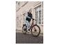 Une femme roule à vélo électrique rose avec un porte-bagages.