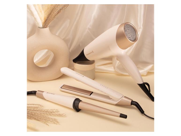 Sèche-cheveux, fer à lisser et fer à boucler blancs et dorés sur fond crème.
