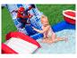 Fille jouant dans une piscine gonflable avec toboggan et thème de super-héros.