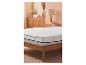 Protège-matelas blanc avec élastiques sur un lit en bois.