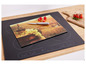 Une planche à découper en verre avec une image de vin et de raisin, sur une plaque de cuisson à induction noire.