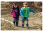 Deux enfants portent des vestes, des t-shirts et des pantalons à l'extérieur dans la nature.