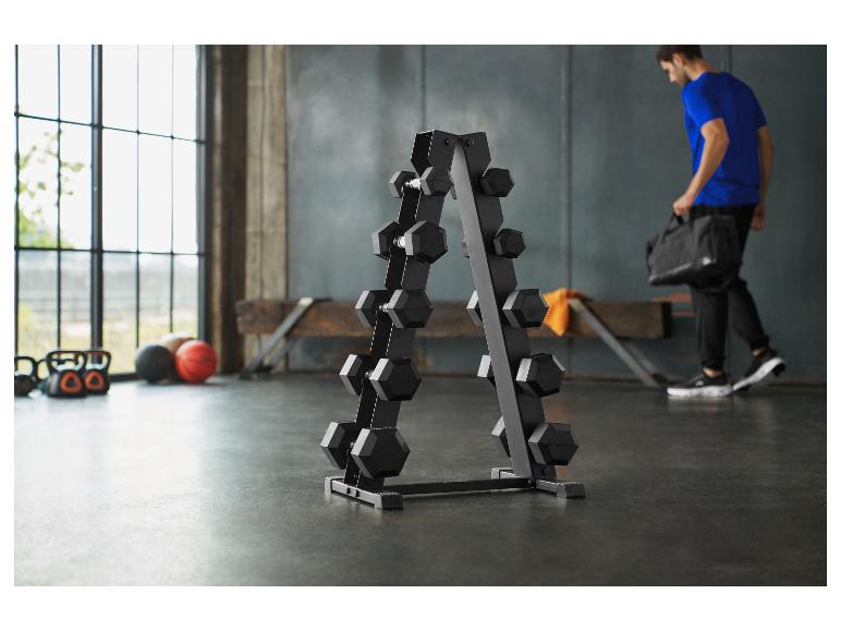 Une salle de sport avec un support d'haltères, des kettlebells et des ballons, avec un homme portant un sac de sport.