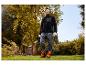 Un homme dans un jardin portant une veste polaire noire PARKSIDE® et un pantalon de travail.