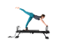 Une femme s'entraînant sur un appareil de Pilates reformer noir