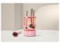 Nettoyeur de pinceaux de maquillage rose avec pinceaux à l'intérieur, à côté d'un pinceau sale et de poudre.