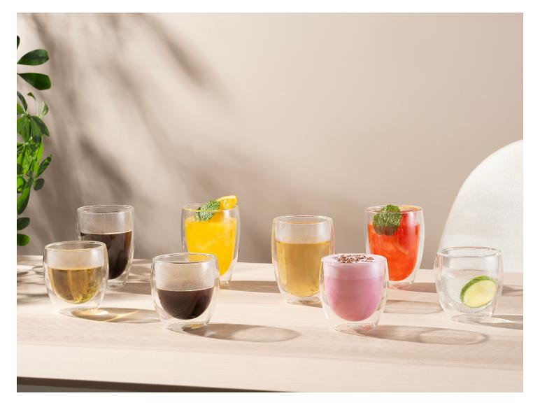 Diverses boissons dans des verres à double paroi sur une table en bois avec lumière naturelle.