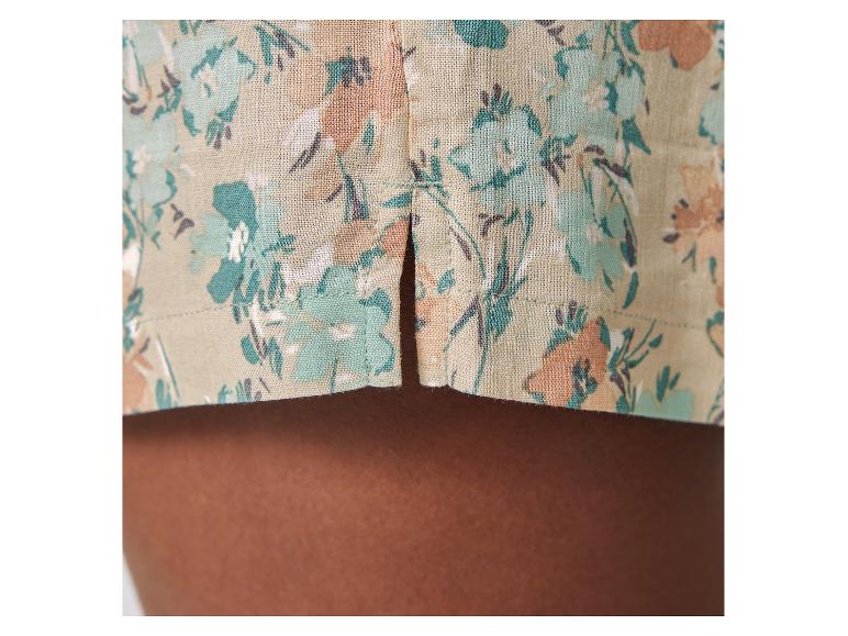 Détail d'un vêtement en tissu floral beige et vert.