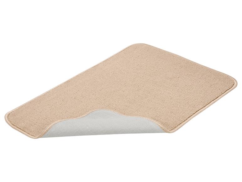 Tapis antidérapant beige avec un coin relevé, montrant le dessous.