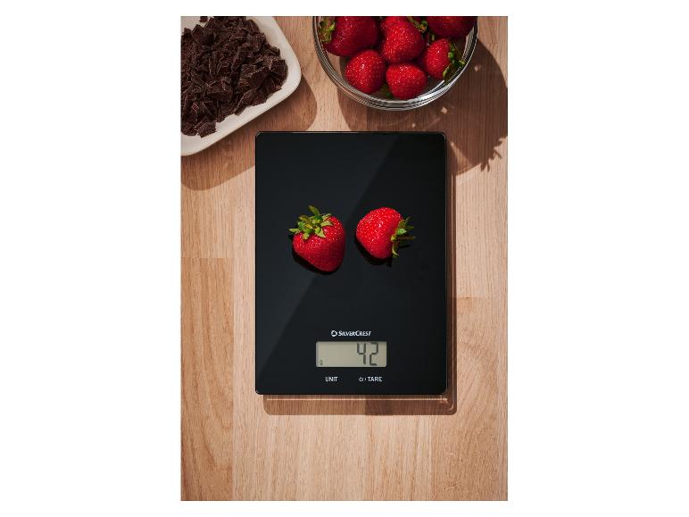 Balance de cuisine SilverCrest pesant deux fraises, avec du chocolat et d'autres fraises à côté.