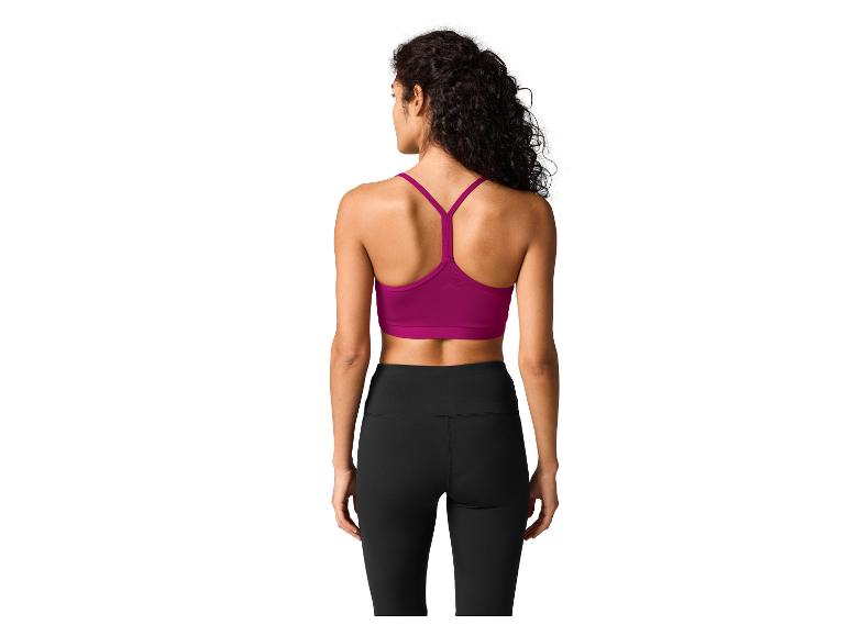 Femme de dos en brassière de sport violette et leggings noirs.