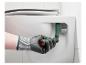 Main gantée utilisant une clé de siège de toilette pour installer un siège de toilette.