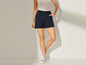 Une femme porte un short bleu foncé et des baskets blanches.