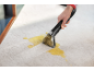 Nettoyeur de tapis portatif enlevant une tache jaune d'un tapis clair.