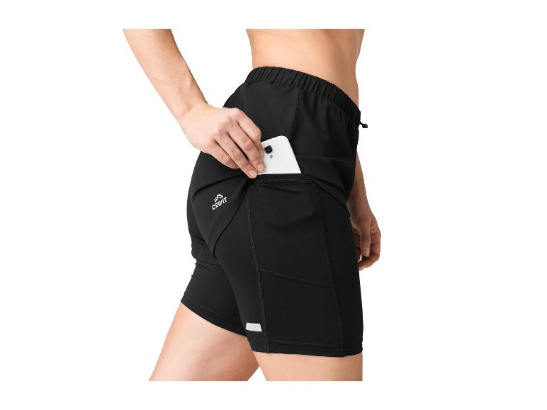Une femme range son téléphone dans la poche de son short de sport noir Crivit.