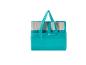 Tapis de plage turquoise plié dans un sac de transport.