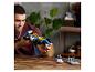 Homme tenant une voiture de course Lego bleue et jaune avec les marques Canon et Goodyear.