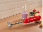 Mixeur plongeant rouge avec verre doseur, baies et smoothie sur une surface en bois.