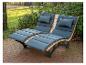 Deux chaises longues avec coussins gris sur une terrasse dans un jardin