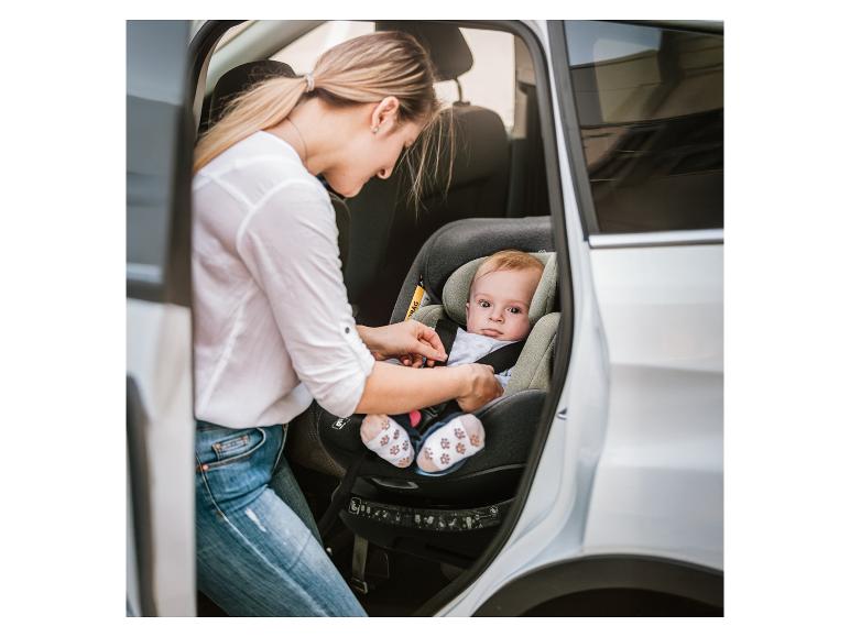 Femme attachant bébé dans un siège auto.