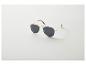 Lunettes de soleil aviateur à monture dorée et verres foncés sur fond blanc.