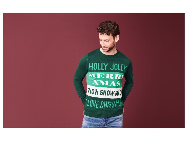 Un homme porte un pull de Noël vert avec l'inscription 'Holly Jolly Merry Xmas'