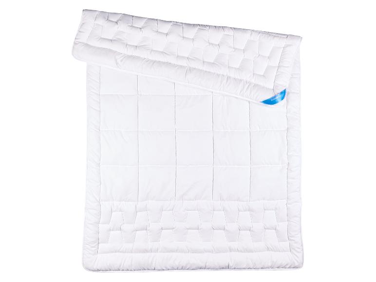 Couette blanche matelassée avec un motif géométrique et une étiquette bleue.