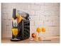 Machine à granité noire avec boisson orange, verres et pêches sur un comptoir en bois.