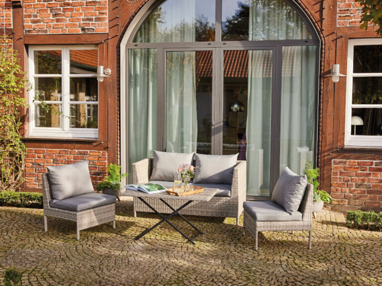 Mobilier de jardin avec des coussins gris sur une terrasse en pavés.