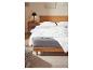 Une couette blanche sur un lit en bois avec un matelas gris.