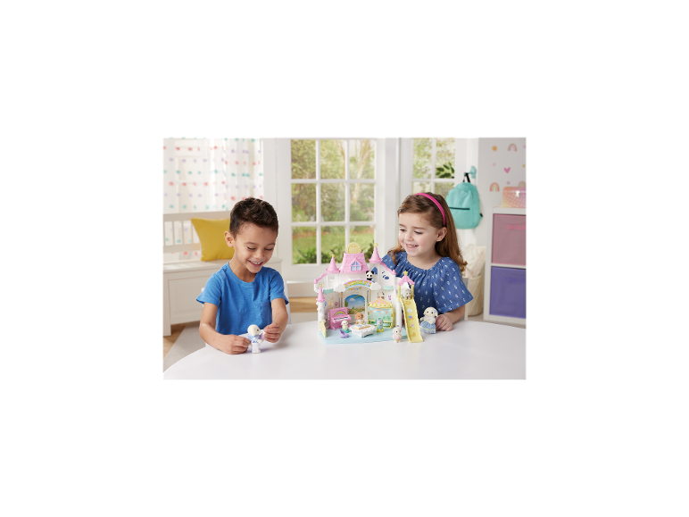 Deux enfants jouent avec un ensemble de jouets animaux, avec un château et un toboggan.