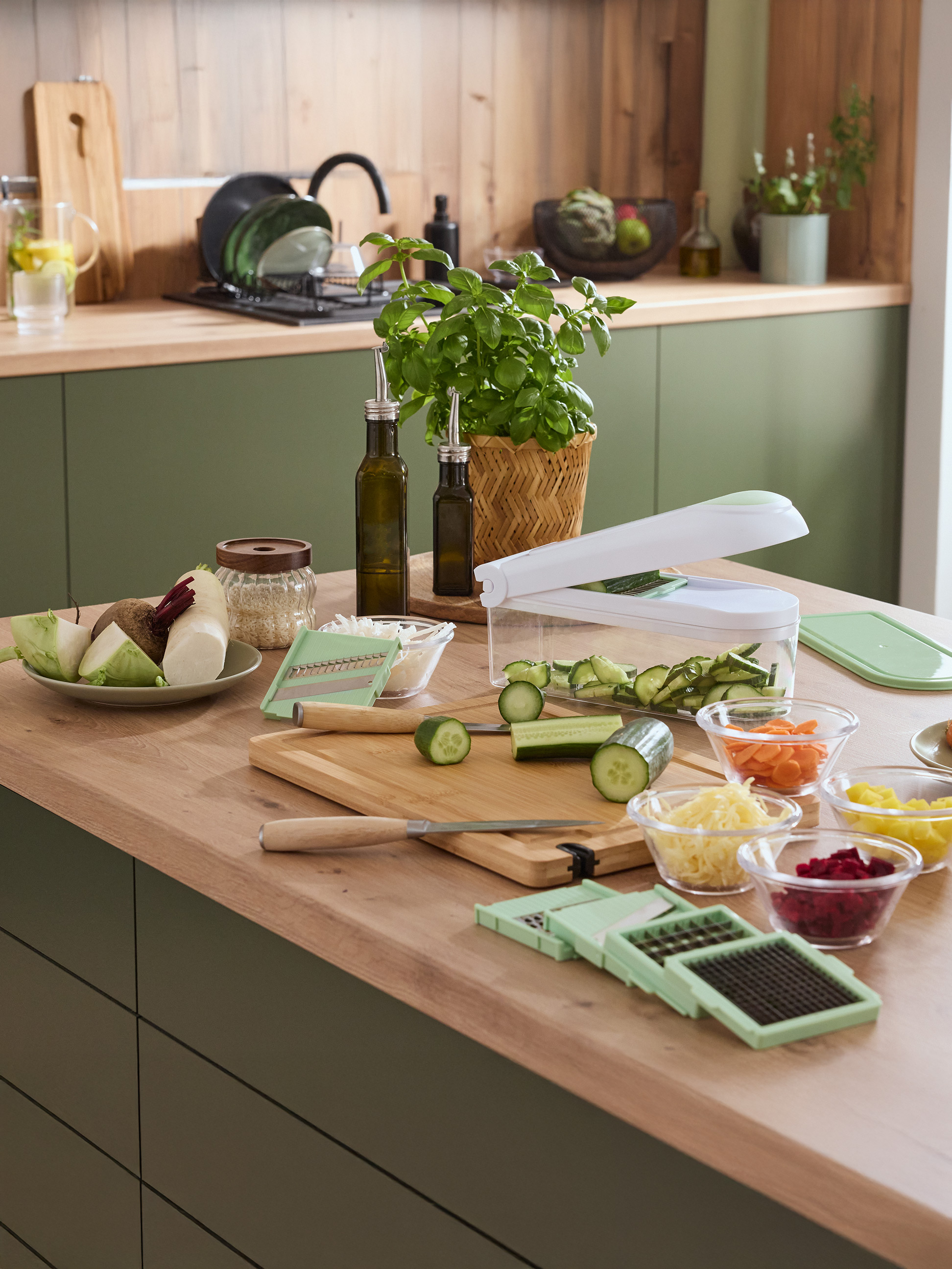 Comptoir de cuisine avec une trancheuse à légumes, des légumes frais et des herbes.