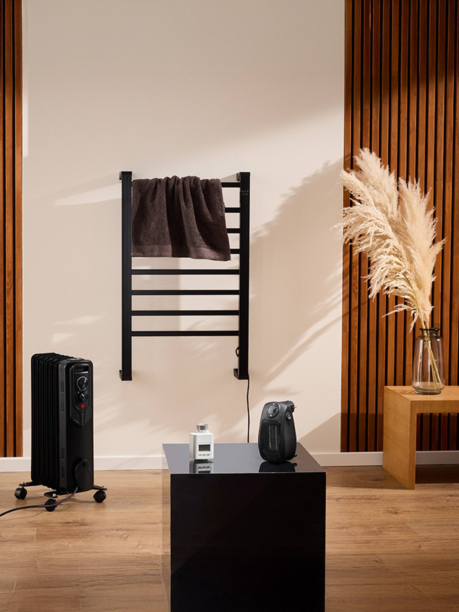 Un radiateur électrique noir et un sèche-serviettes mural dans une salle de bain moderne.