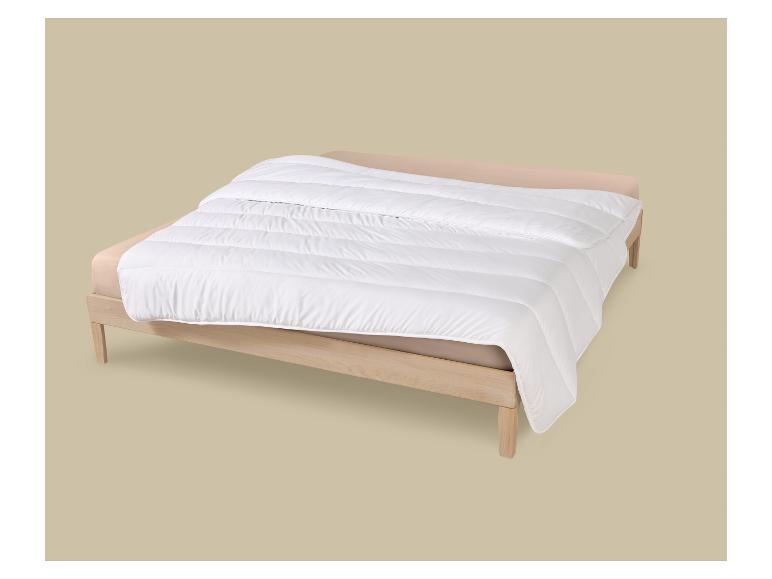 Couette blanche sur un lit en bois avec des draps beiges