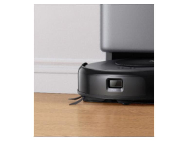 Robot aspirateur noir avec station de charge sur un parquet.