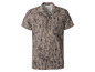 Une chemise beige à manches courtes avec un motif noir abstrait.