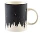 Une tasse blanche avec une image noire d'une forêt et d'oiseaux.