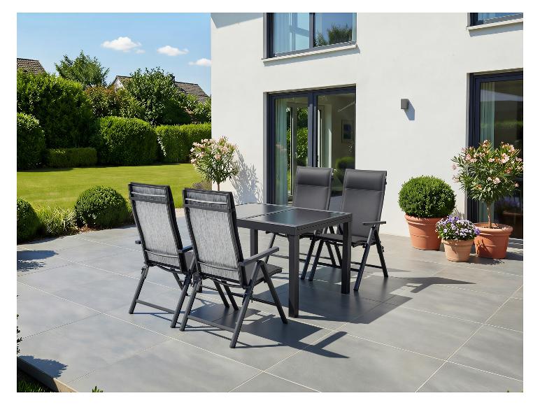 Ensemble de mobilier de jardin sur la terrasse: table et quatre chaises, entouré de verdure.