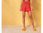 Femme portant des tongs oranges et un short avec un motif abstrait.