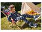 Un jeune garçon profite d'une journée ensoleillée assis sur une chaise longue en bois avec un motif cerises.