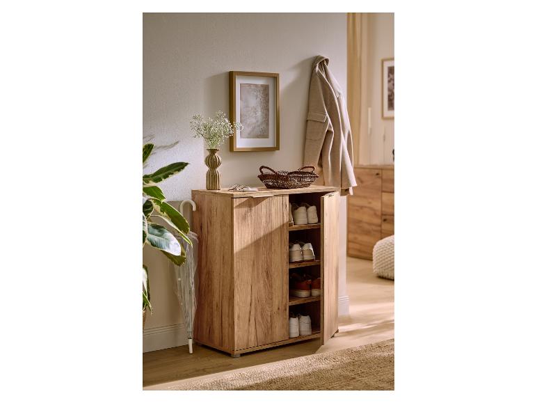 Meuble à chaussures en bois clair avec porte ouverte, montrant des chaussures, dans un couloir douillet.