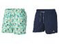 Deux shorts de bain pour hommes : un à imprimé citrons et un bleu foncé.