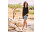 Une femme porte un débardeur noir, un short en jean et des espadrilles.