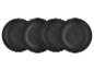 Quatre assiettes plates noires en céramique texturée, légèrement superposées.