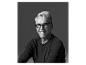Homme souriant avec des lunettes, cheveux gris, en chemise noire.